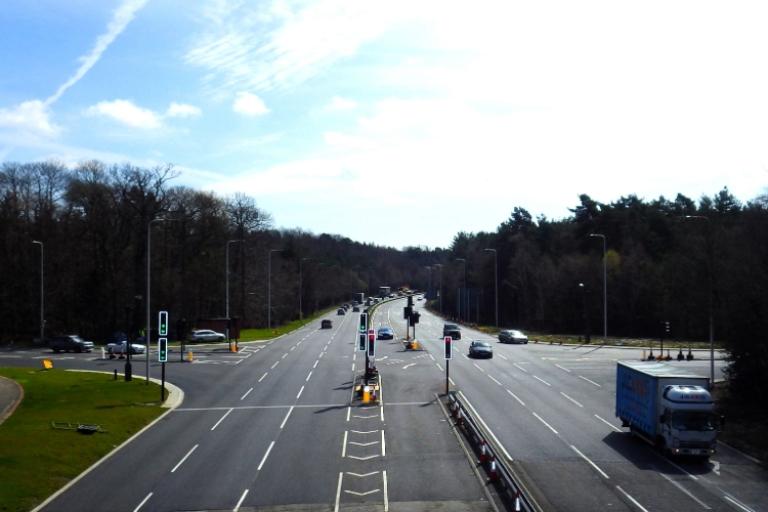 Crossroads with vans and cars coming from all directions with trees along the sides. 