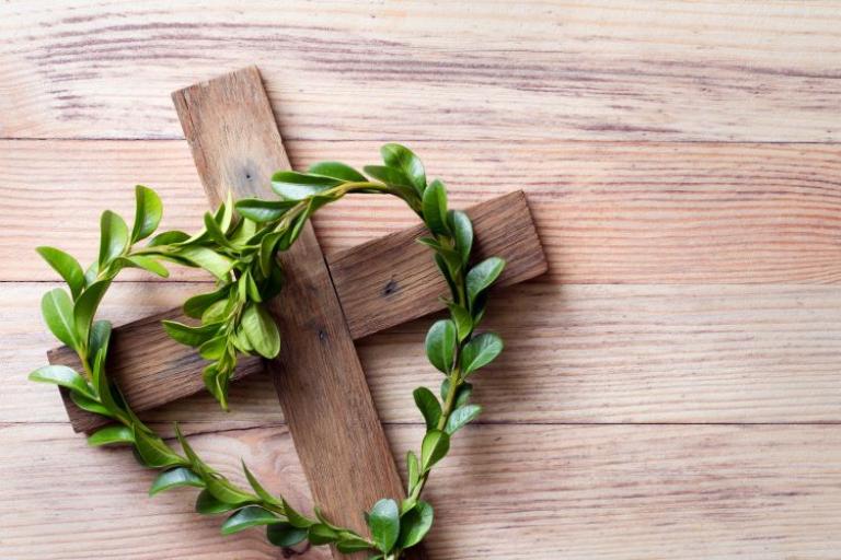 Wooden cross with sprigs of boxwood in heart-shaped, easter symbol of life