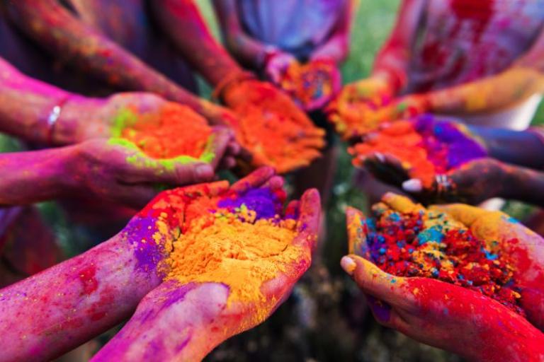 Hands holding different colours of bright powder paint