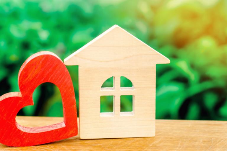 A wooden cut out of a red heart next to a wooden cut out of a house with pointy roof