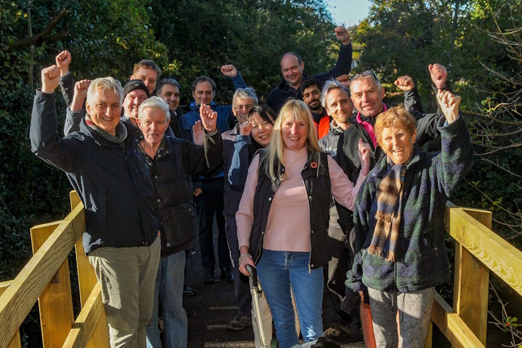 A group of people stand on a bridge with their hands in the air.
