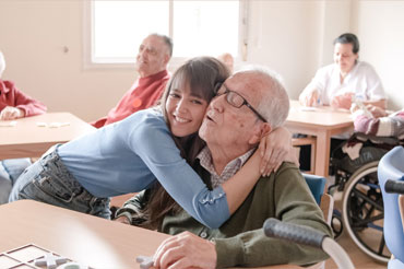 young carer embracing her elderly grandfather