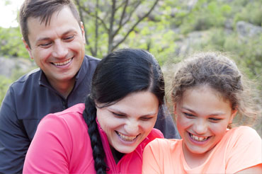 Smiling family in park - father, mother and daughter