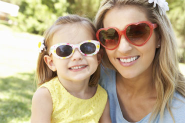 Mother and daughter on sunny in day in park, both wearing sunglasses