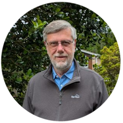 Colin Bird, the chair of the LCAF, standing in front of green trees.