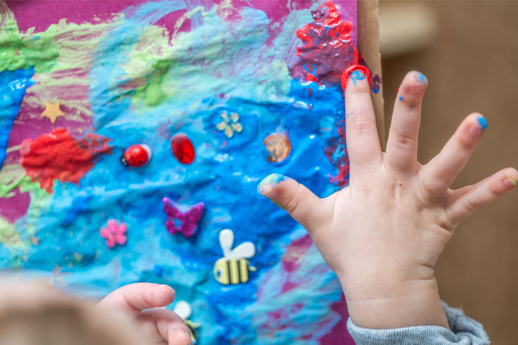 Toddler's hands and art project with finger paints
