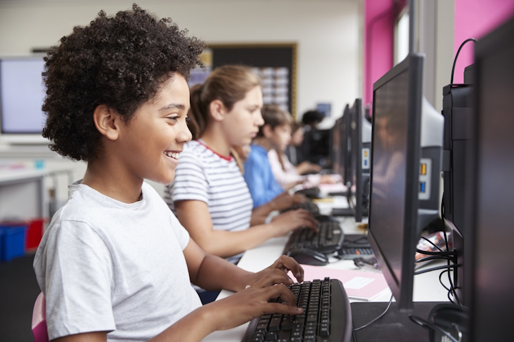 A row of children on computers.