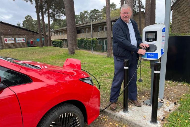 Cllr Turrell plugging EV car into charging point