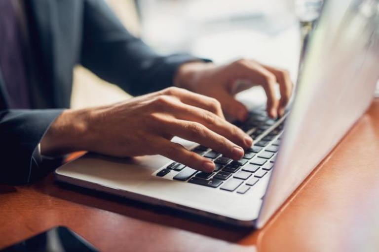 Two hands typing on a laptop keyboard.