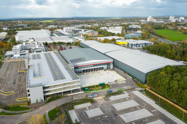 Selection of industrial and office buildings in front of some open green space and residential buildings in the background. 