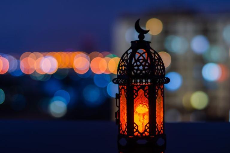 A lantern with a candle in it against a dark background