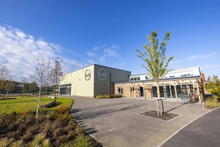 community centre building surrounded by grass and trees under a blue sky