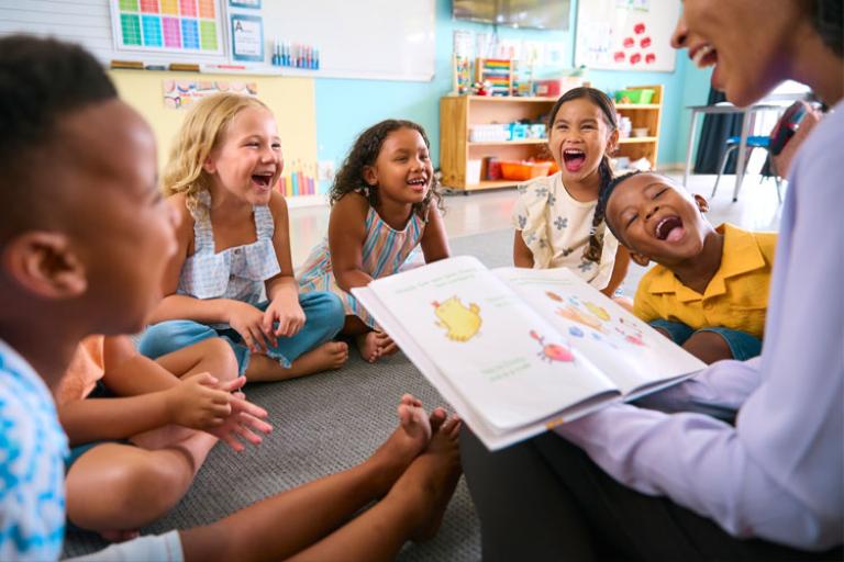 Smiling adult reading a story to happy kids sitting on a carpet
