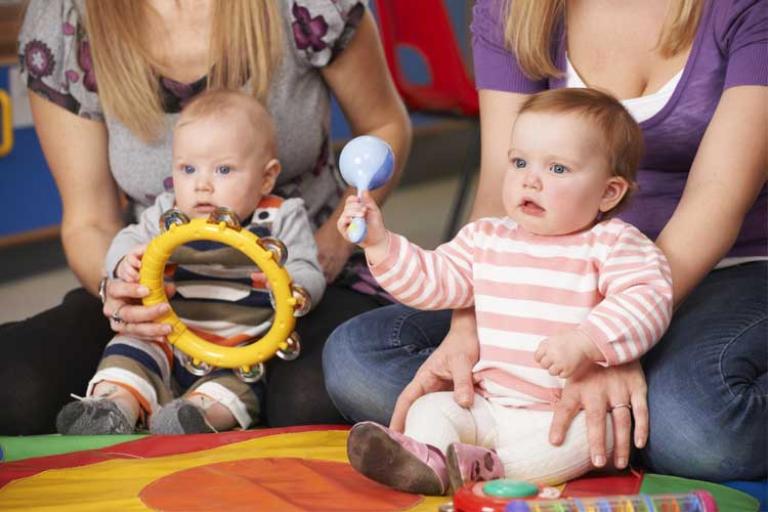 two babies with their mothers holding a tambourine and rattle