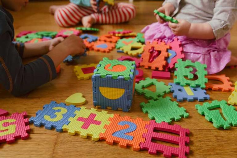 Toddlers playing with colourful sensory jigsaw numbered mats