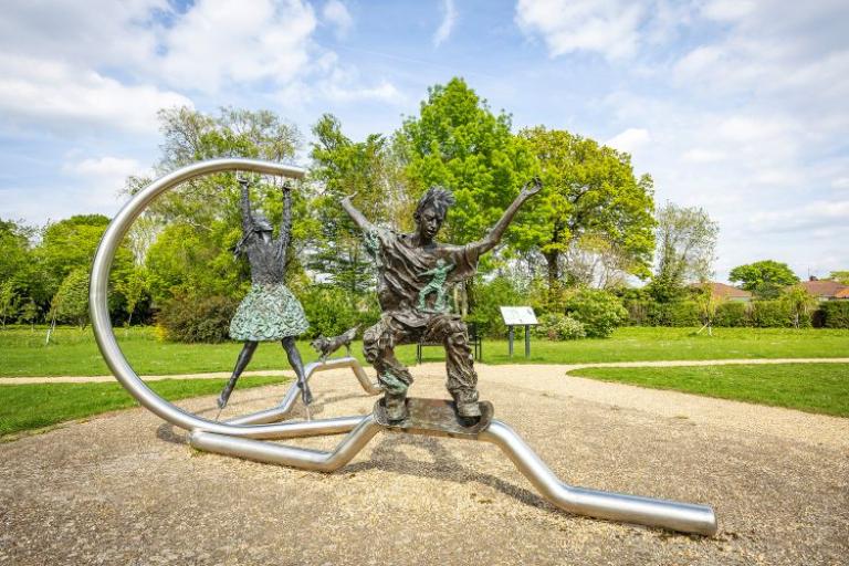 a metal sculpture of a boy on a skateboard and a girl hanging from a pole