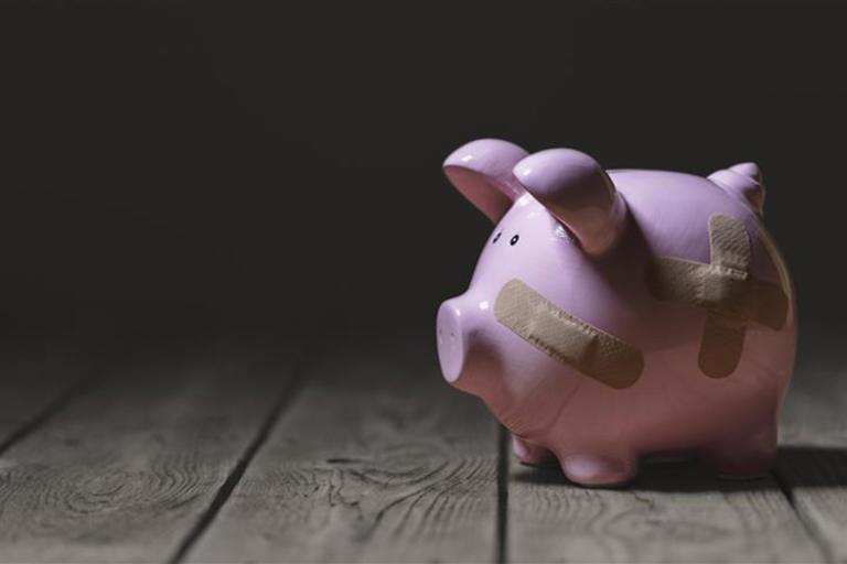 A pink piggy bank with plasters over it