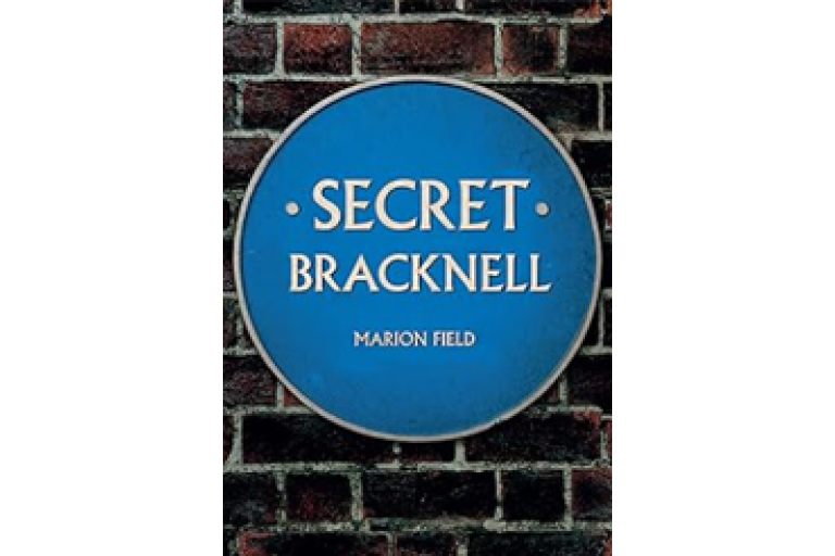 Blue circular sign on a brick wall reading “Secret Bracknell” with the author name Marion Field below