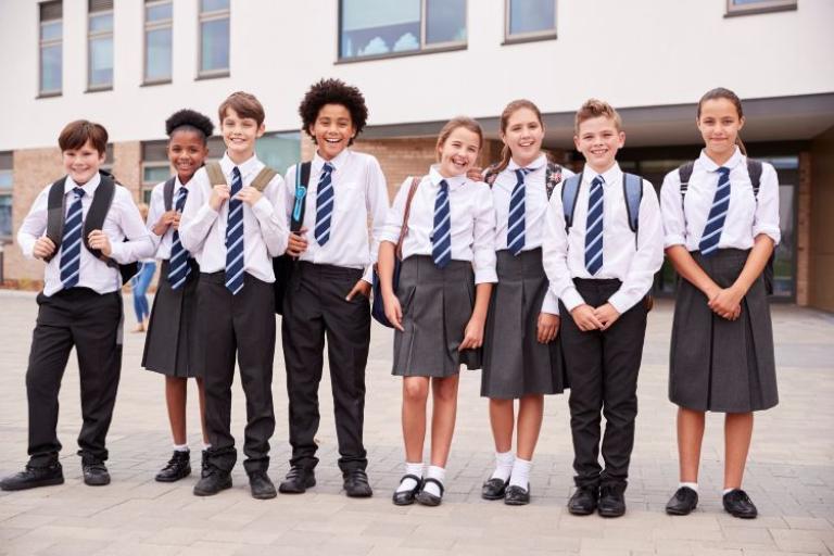 eight children in school uniform standing outside of a school