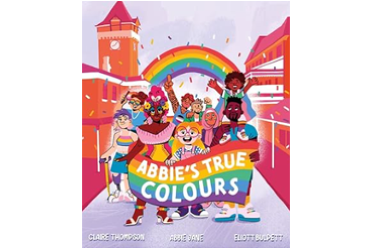 Colourful illustrated book cover titled “Abbie’s True Colours,” showing a diverse group of children celebrating under a rainbow in a bright city scene