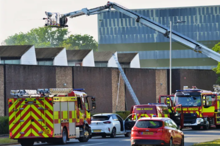 fire trucks including an aerial crane and cars outside an industrial unit