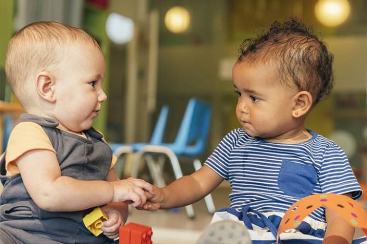 Two babies sitting and playing together