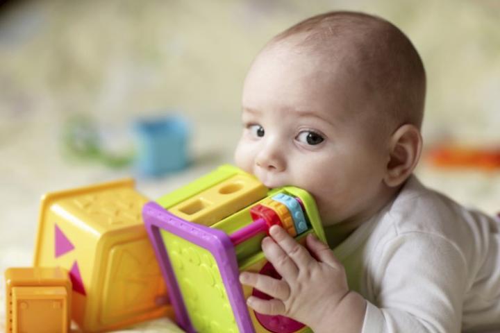 Baby holding toy to mouth