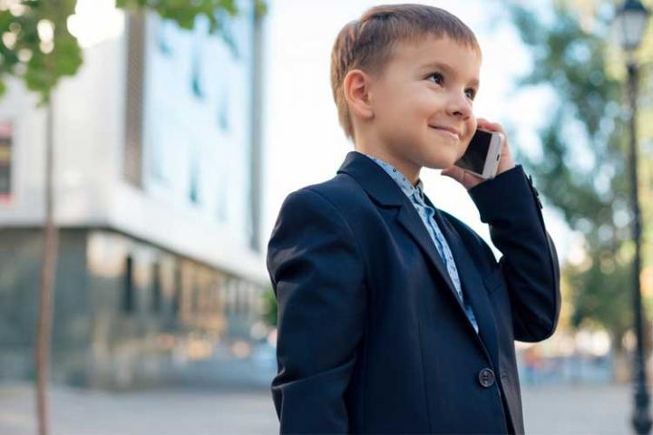 Child in business suit holding smartphone