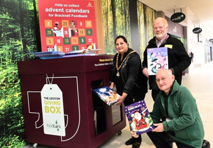 A lady and two men putting advent calendars in a donation box at The Lexicon shopping centre