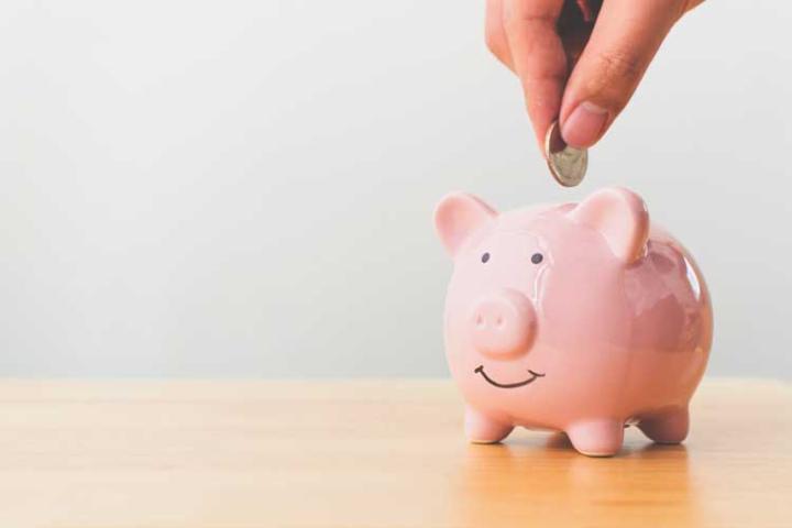 Pink piggy bank with a hand putting a coin in.
