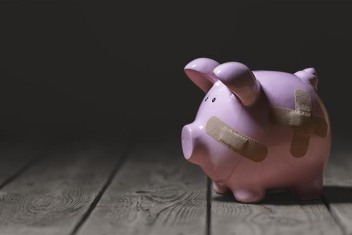 A pink piggy bank with plasters over it