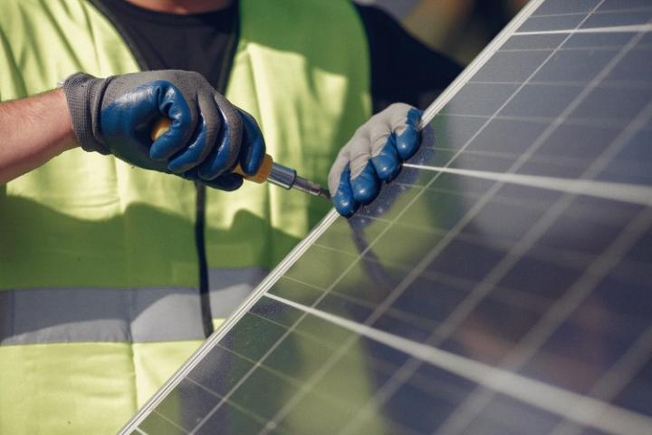 Image of an installers hands fitting a solar panel onto a roof
