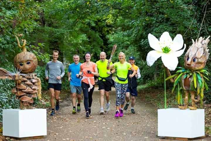 Group of people happily running through a forest with wooden sculptures either side