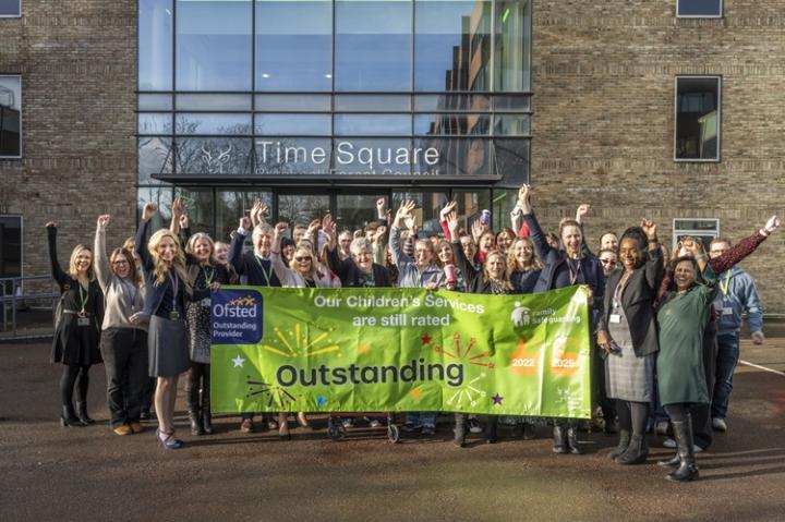Children's social care team standing outside the Time Square building holding a banner saying 'outstanding'.
