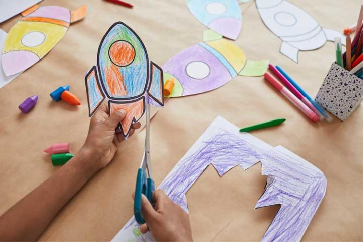 Child cutting out a coloured picture of a rocket