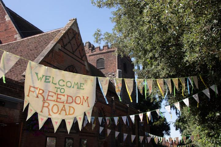 Bunting and a banner in neutral colours hung outside the Colchester Arts Centre. The banner in the middle reads "Welcome to Freedom Road".