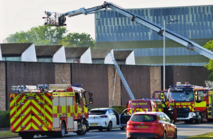 fire trucks including an aerial crane and cars outside an industrial unit
