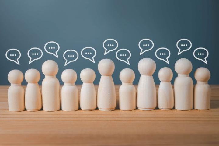 A row of little wooden people with speech bubbles above their heads.