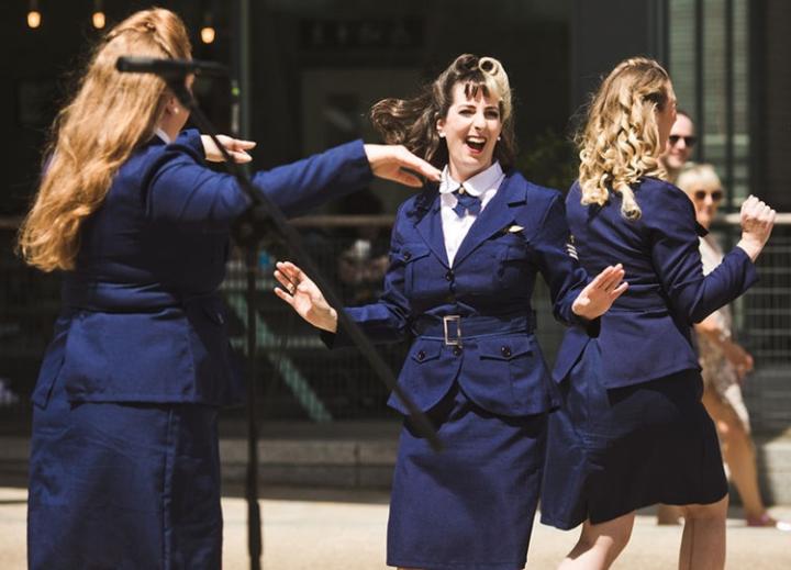 Three women dancing wearing navy blue vintage 1940s suits