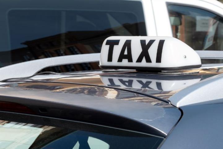 A white and black taxi sign on top of a car roof 