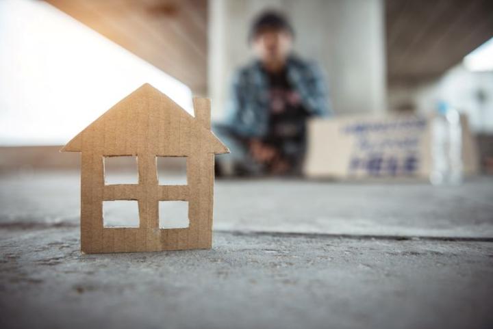 a cardboard cut out of a house with a homeless person in the background
