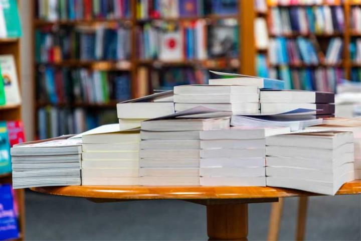 piles of book on a table in a library
