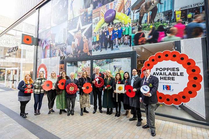 Group of people holding large red poppies in The Lexicon Bracknell