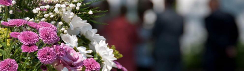 Bouquet of flowers with a funeral service in the background.