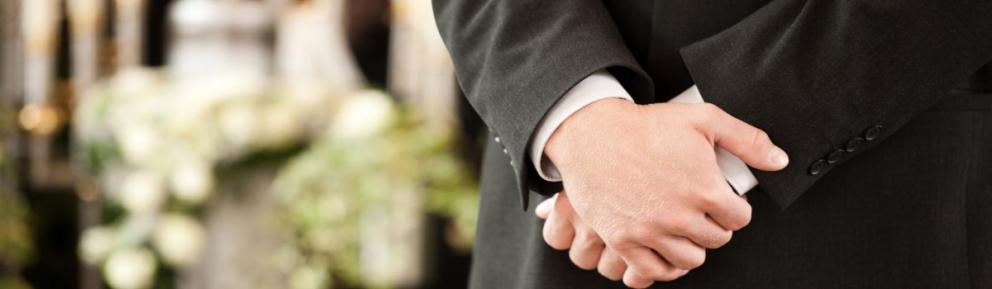 Close up of funeral director's clasped hands.