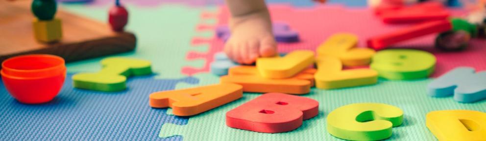 Colourful letters on playmat with babies foot