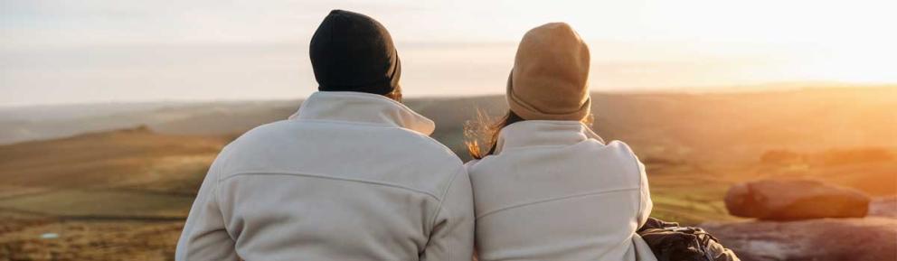 Warmly dressed couple with woolly hats looking over beautiful countryside