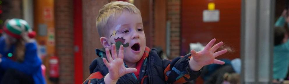 Toddler with hands up having been playing in sand