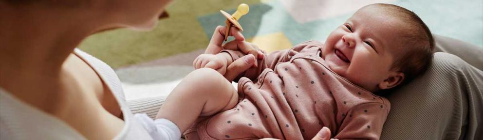 Baby on lap smiling up at woman