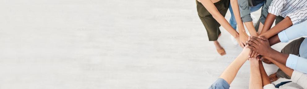 A number of people put their hands together in a circle.